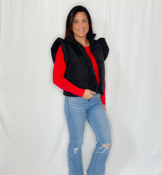 Person wearing a black and red jacket with blue jeans on a white background