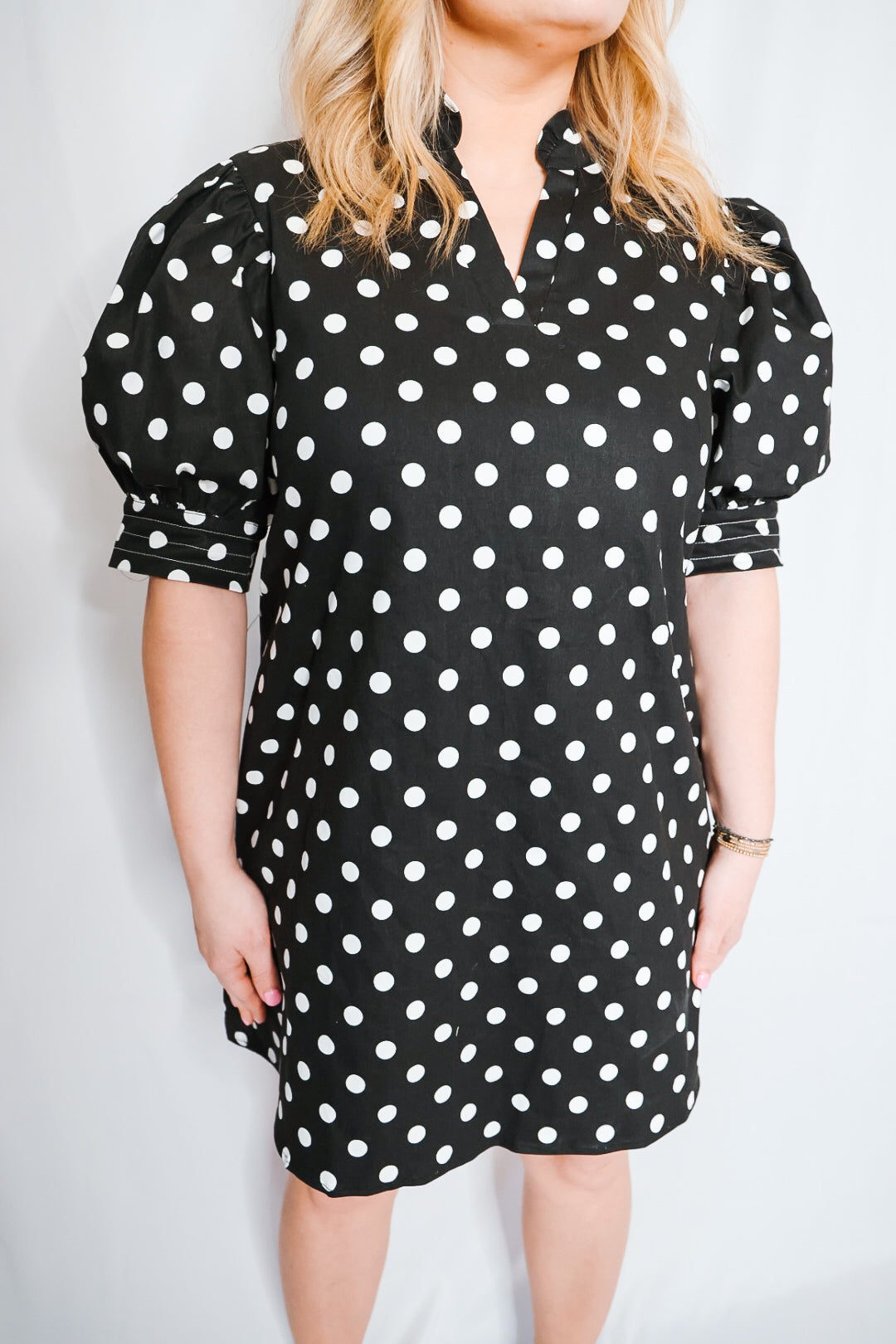 Black polka dot dress worn by a person on a white background
