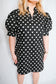 Black polka dot dress worn by a person on a white background
