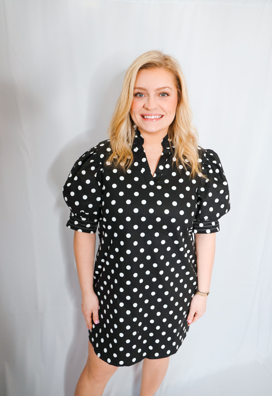 Woman wearing a black polka dot dress against a plain background