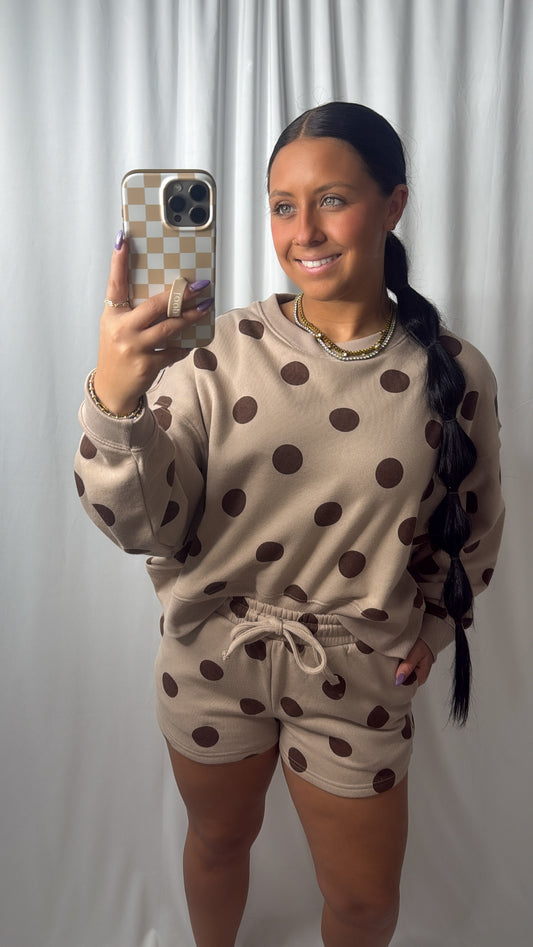 A woman taking a selfie in a mirror with a brown two piece set 