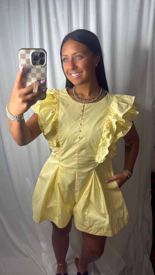 A women wearing a butter yellow ruffle sleeve romper with pockets, a fitted waist, and a button front detail