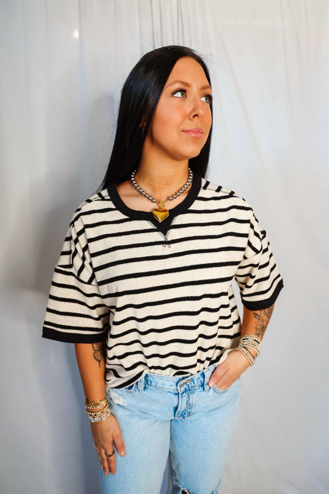 Woman wearing a black and white striped shirt with light blue jeans against a plain background