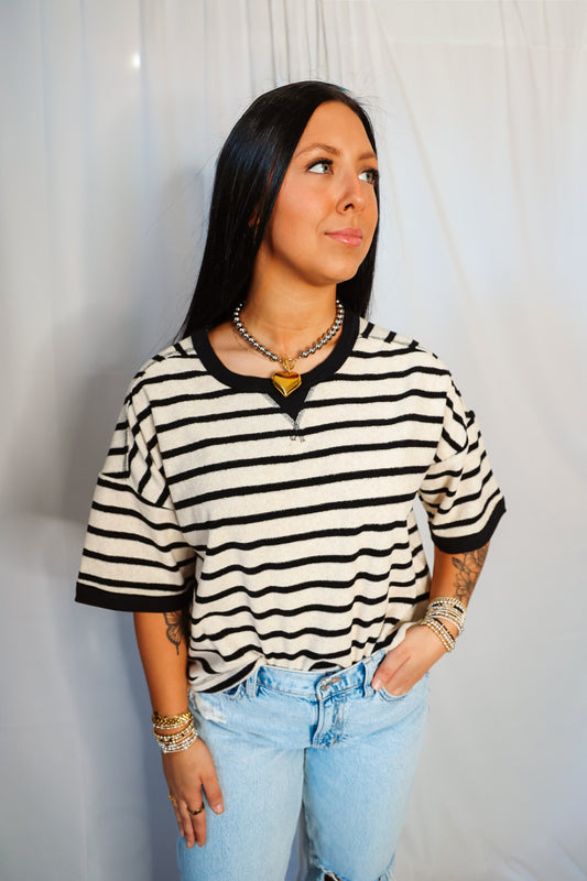 Woman wearing a black and white striped shirt with light blue jeans against a plain background