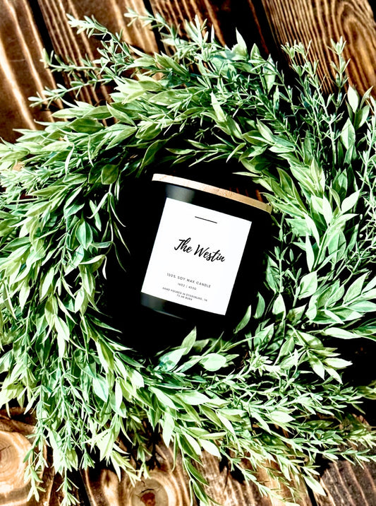 Candle labeled 'The Westin' on a decorative wreath with green leaves