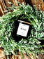 Candle labeled 'The Westin' on a decorative wreath with green leaves