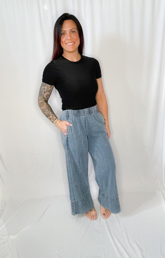 Woman wearing a black t-shirt and light blue jeans against a white background