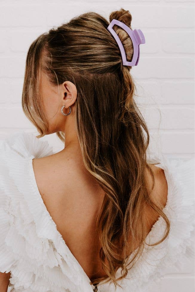 Person with long hair tied back with a purple hair clip on a white background