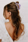 Person with long hair tied back with a purple hair clip on a white background
