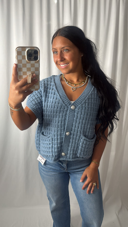 A women wearing a blue cardigan with buttons on a white background