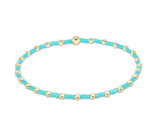 Turquoise and gold beaded bracelet on a white background