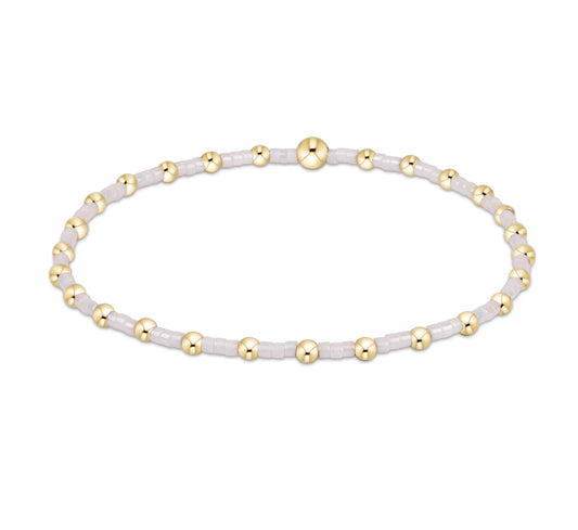 Bracelet with white beads and gold accents on a white background