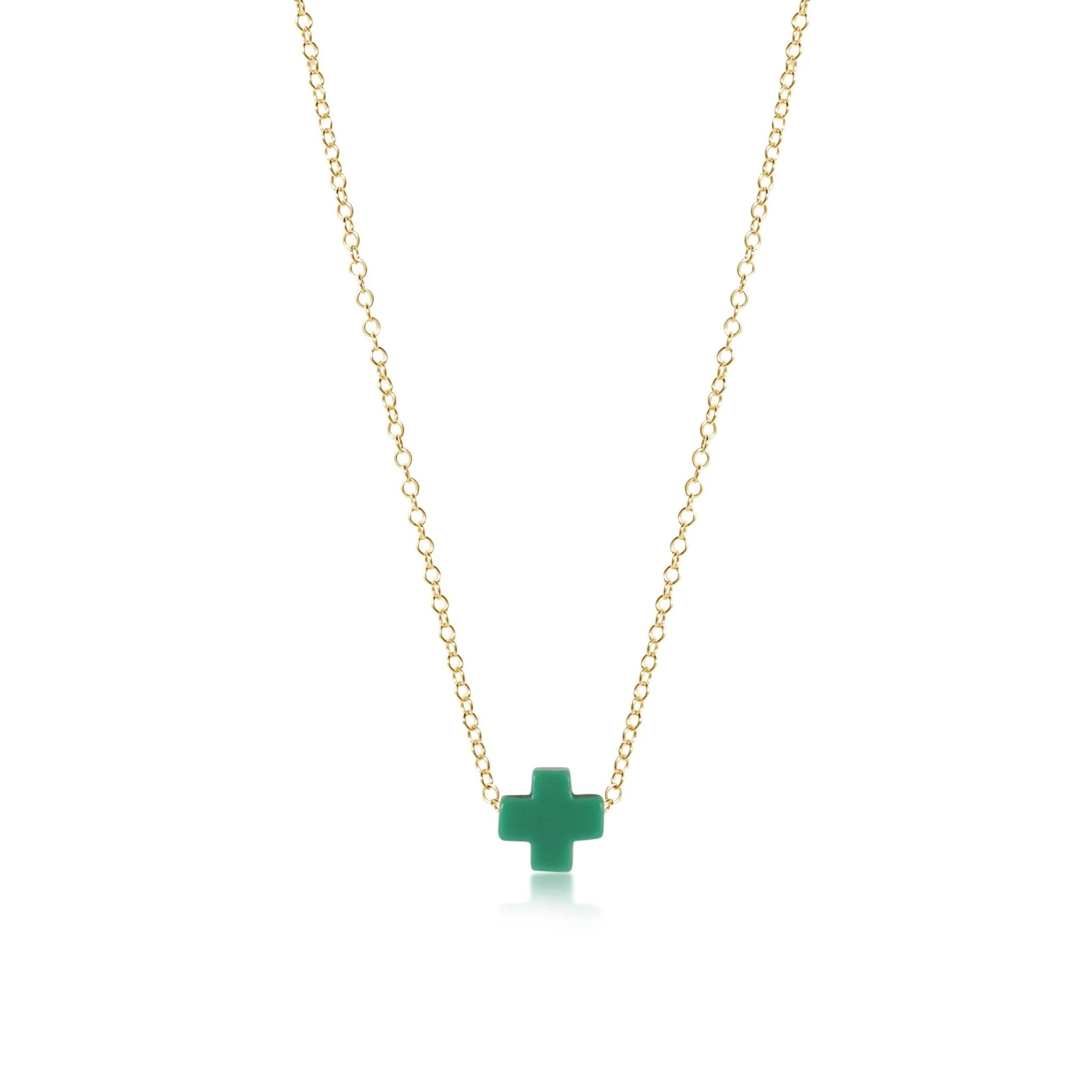 A gold enewton necklace with a green cross pendant on a white background.