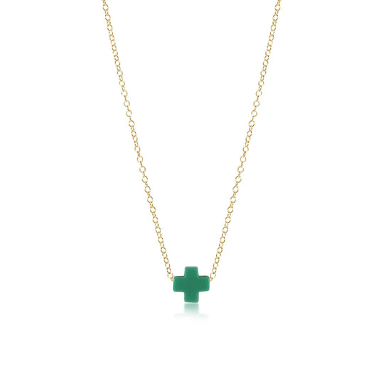 A gold enewton necklace with a green cross pendant on a white background.