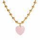 Gold beaded necklace with a pink heart pendant on a white background