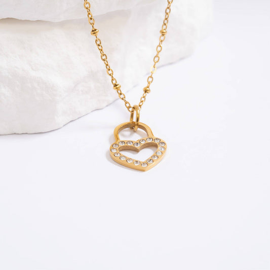 Gold heart-shaped necklace with embedded stones on a white background