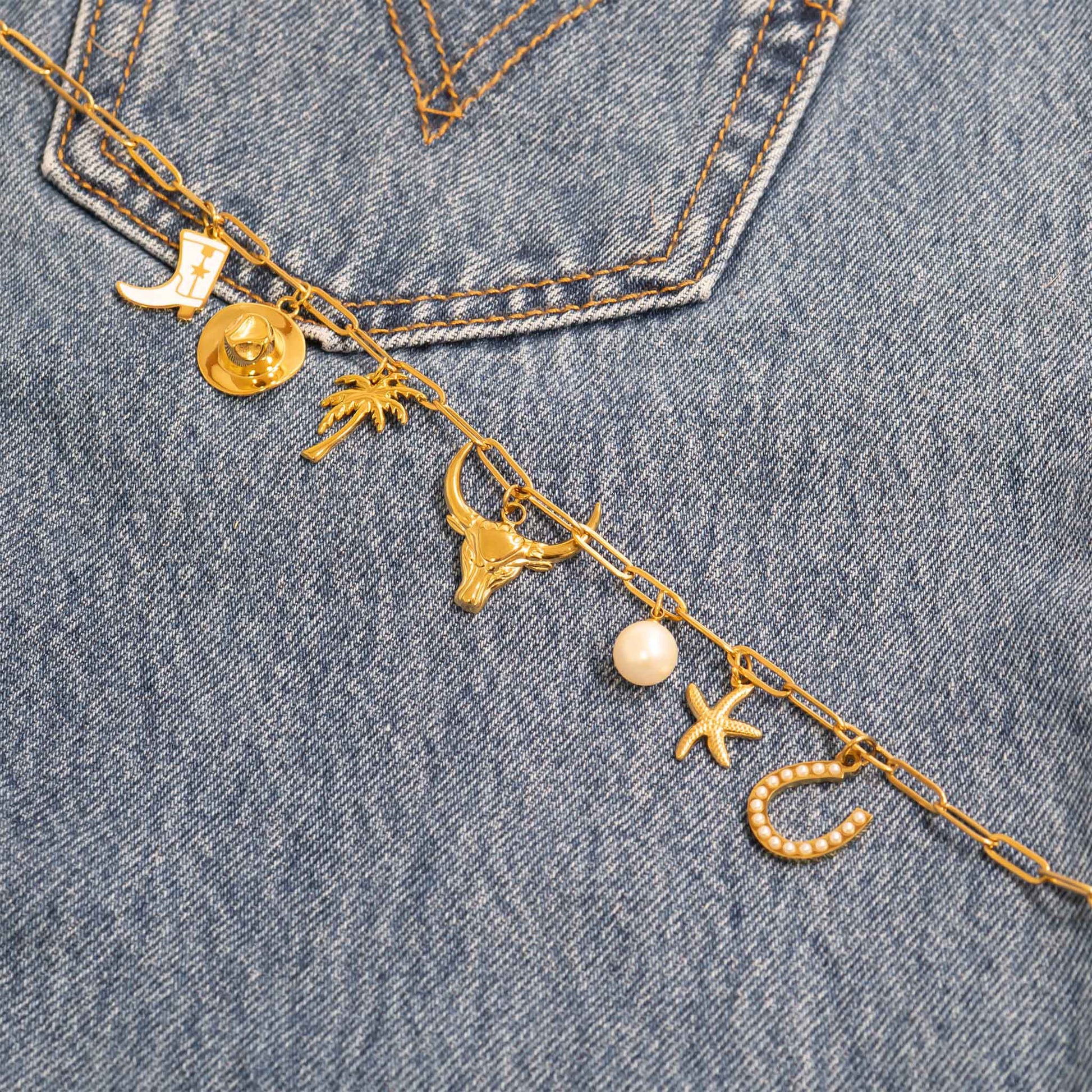 Gold paperclip chain with charms on a denim background