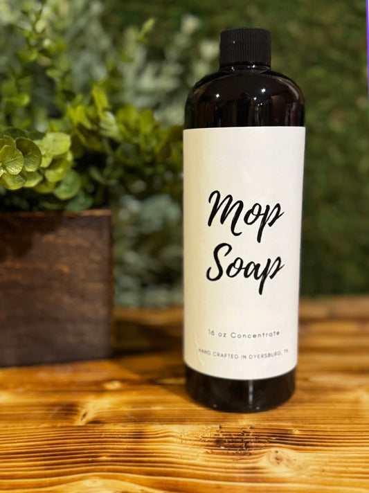 Bottle of Mop Soap on a wooden surface with greenery in the background