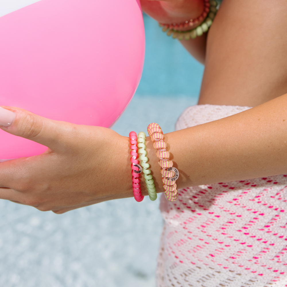 Close-up of a person's wrist wearing colorful teleties worn as a bracelet with a blurred background.