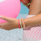 Close-up of a person's wrist wearing colorful teleties worn as a bracelet with a blurred background.