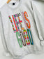 Gray sweatshirt with 'LIFE IS GOOD' text in colorful patterns on a white background