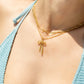 Gold necklace with a bow pendant worn by a person in a blue bikini.