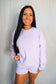 Woman wearing a light purple sweatshirt and shorts set against a plain background