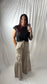 A woman takes a mirror selfie wearing a black short-sleeve t-shirt and beige wide-leg cargo pants with a drawstring waist, set against a white draped fabric backdrop.