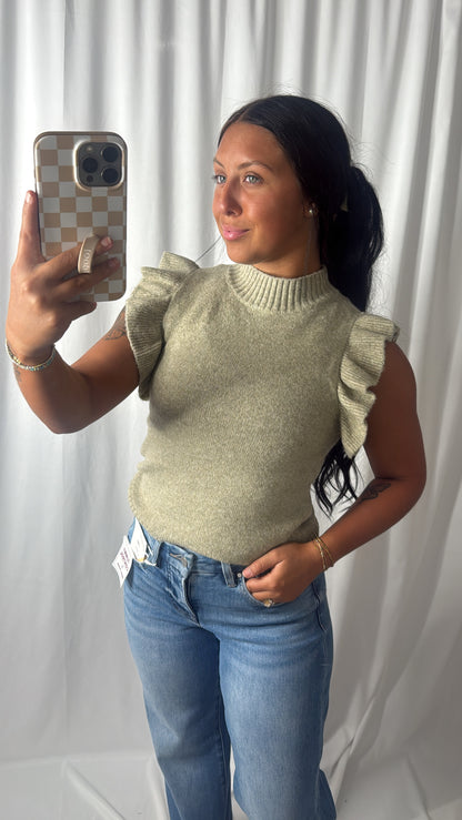 Women's light olive green knit sweater with ruffled sleeves and mock neck, paired with blue jeans