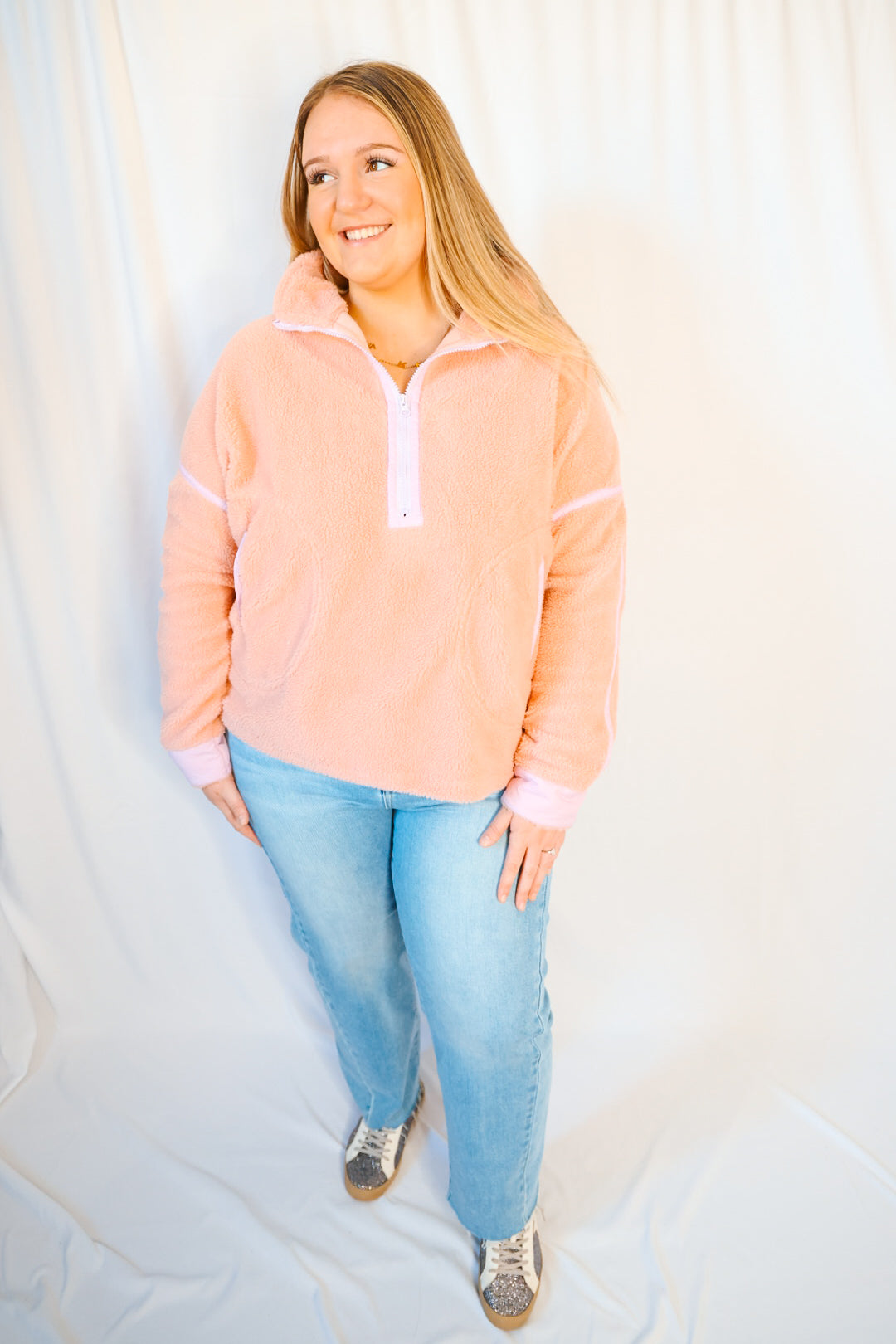 Woman wearing a peach-colored pullover with a white background