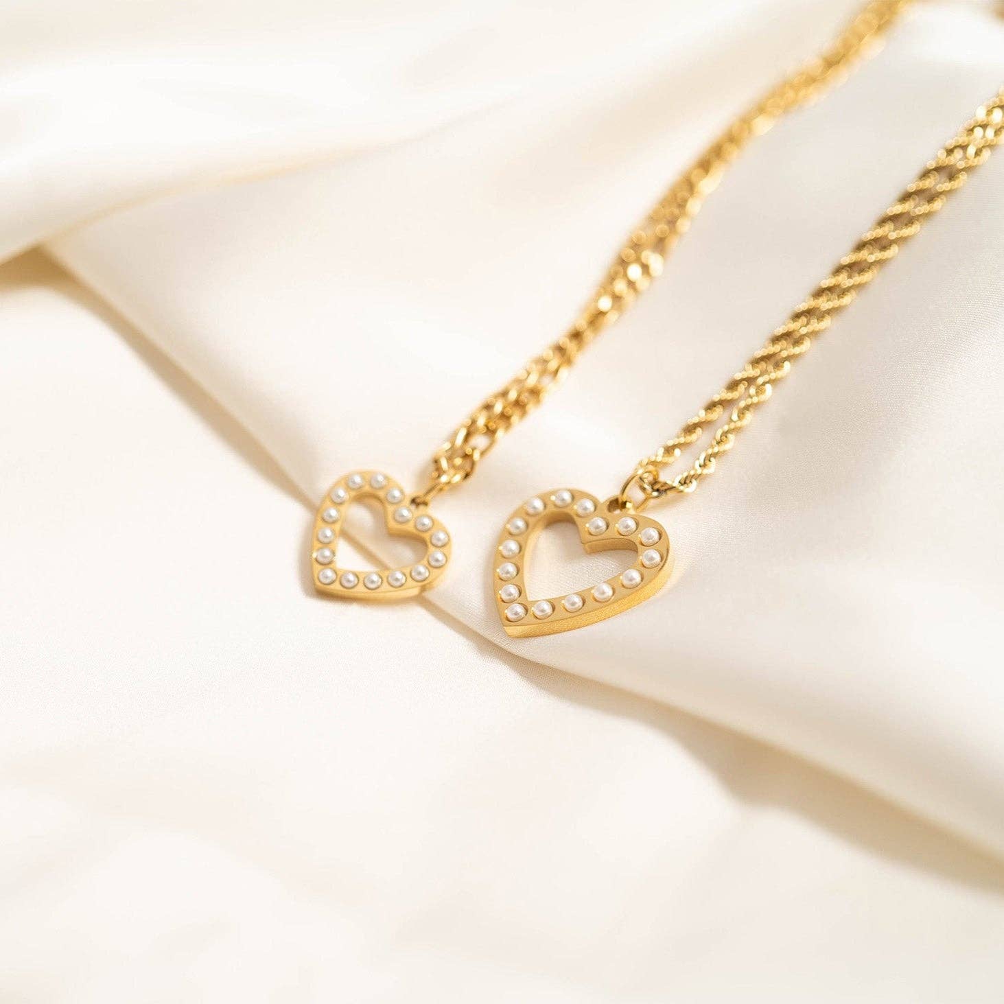 Gold heart-shaped necklace on a soft beige fabric background