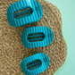 Three blue striped hair clips on a woven mat with a light green background