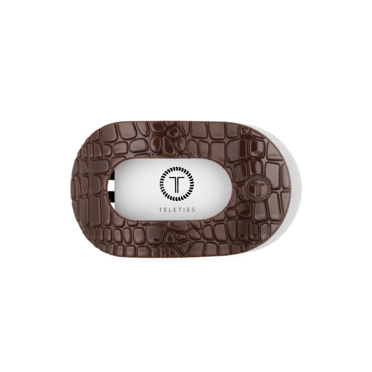 Brown textured case with a white interior for a product, featuring the brand 'Teleties'.