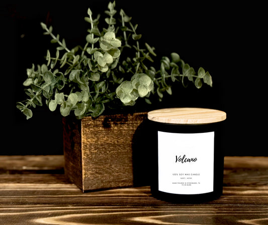 Candle with a wooden lid and eucalyptus plant on a wooden surface