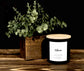 Candle with a wooden lid and eucalyptus plant on a wooden surface