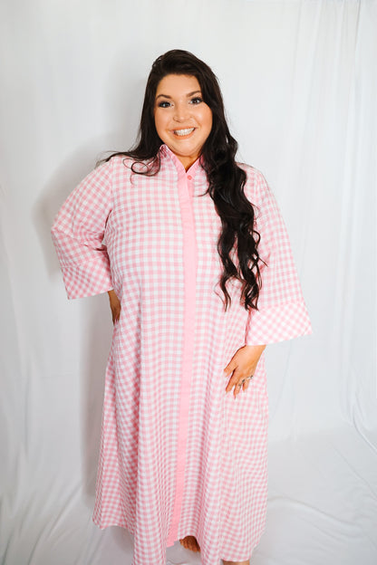 Woman wearing a pink checkered dress against a white background