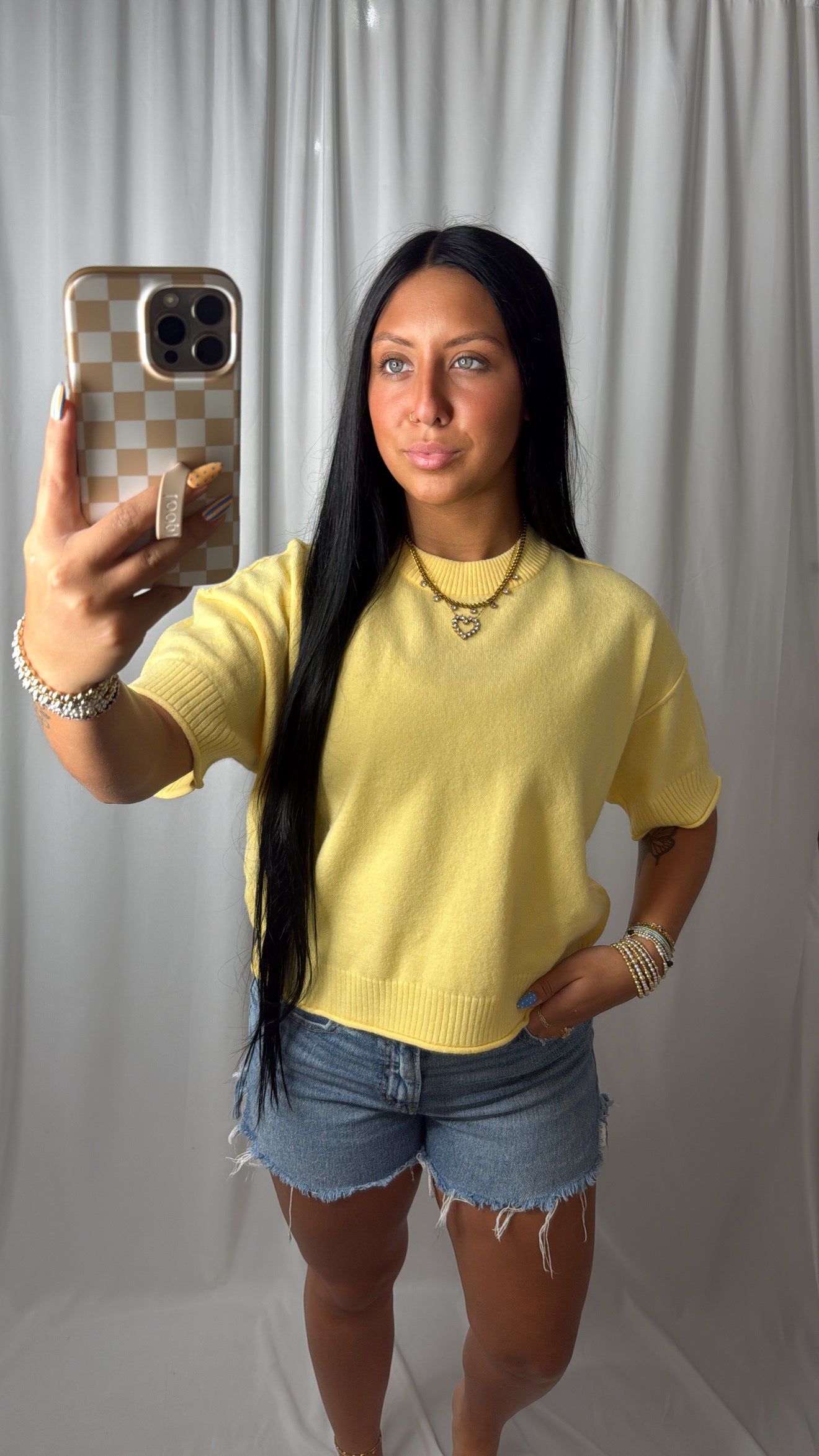 Model wearing a butter yellow short sleeve knit sweater with distressed shorts
