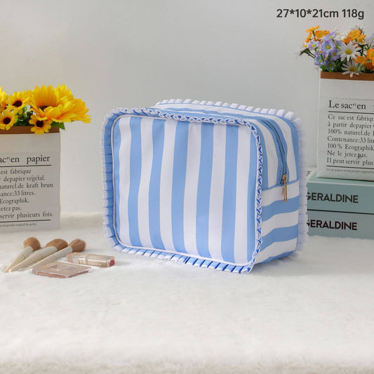 Blue and white striped pouch on a white surface with flowers and books in the background