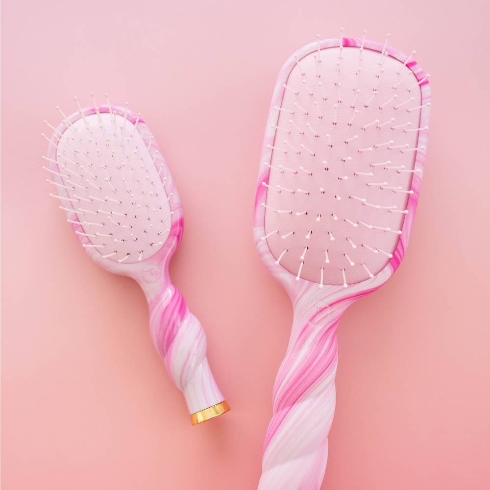 Two pink and white hairbrushes with marble pattern on a pink background