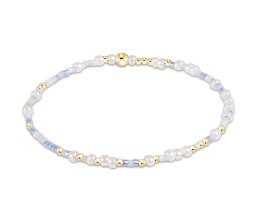 Beaded bracelet with white, gold, and blue beads on a white background