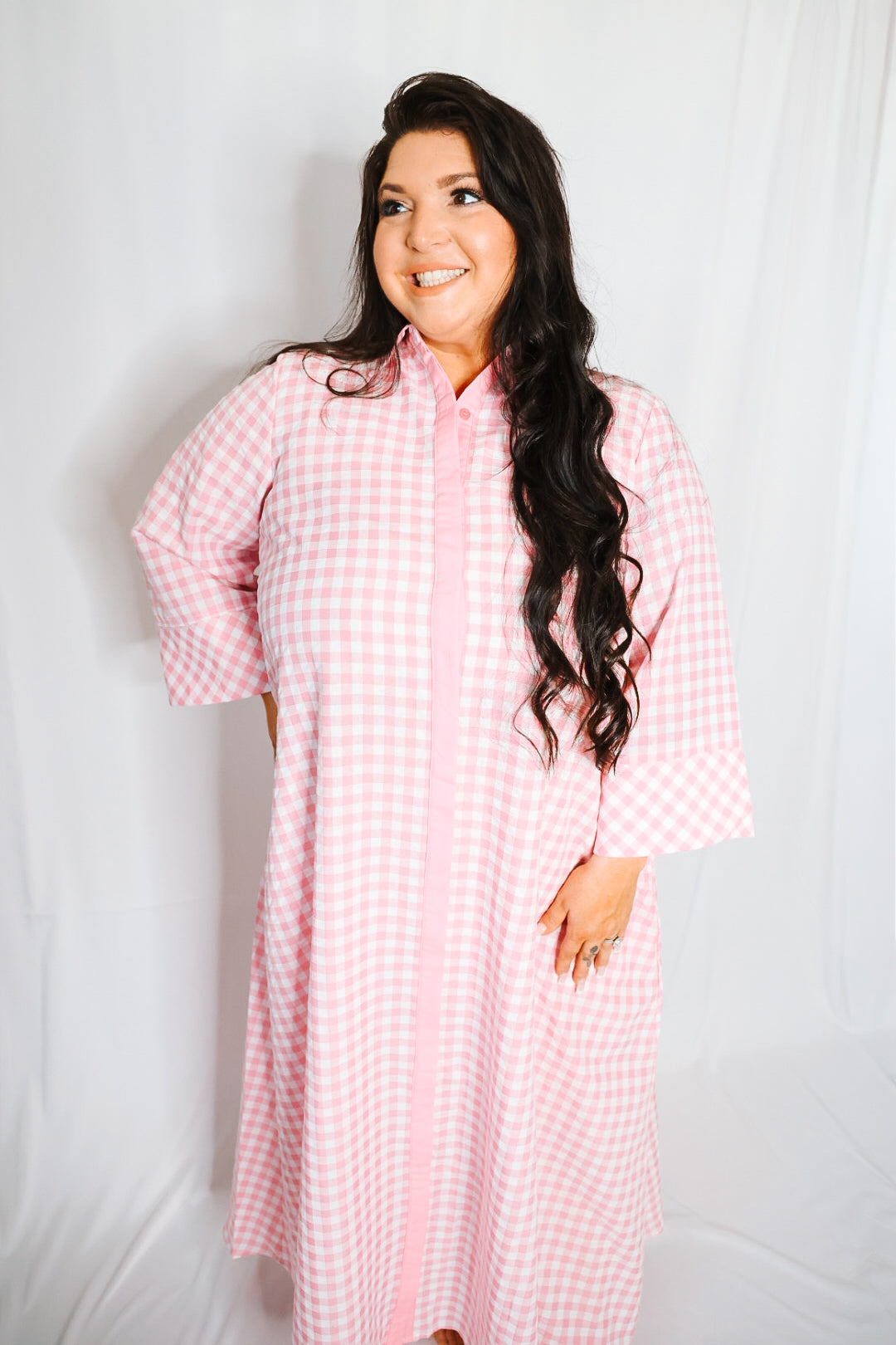 Woman wearing a pink checkered robe against a white background