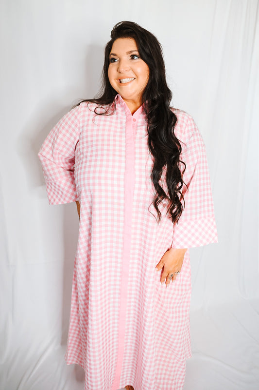 Woman wearing a pink checkered robe against a white background