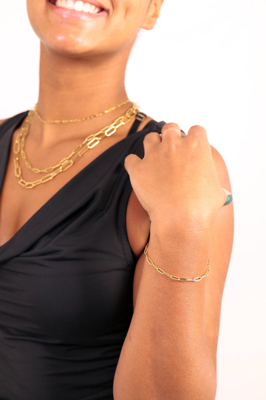 Woman wearing gold necklaces and bracelet on a white background