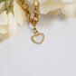 Gold chain bracelet with a heart-shaped charm on a white background with flowers.