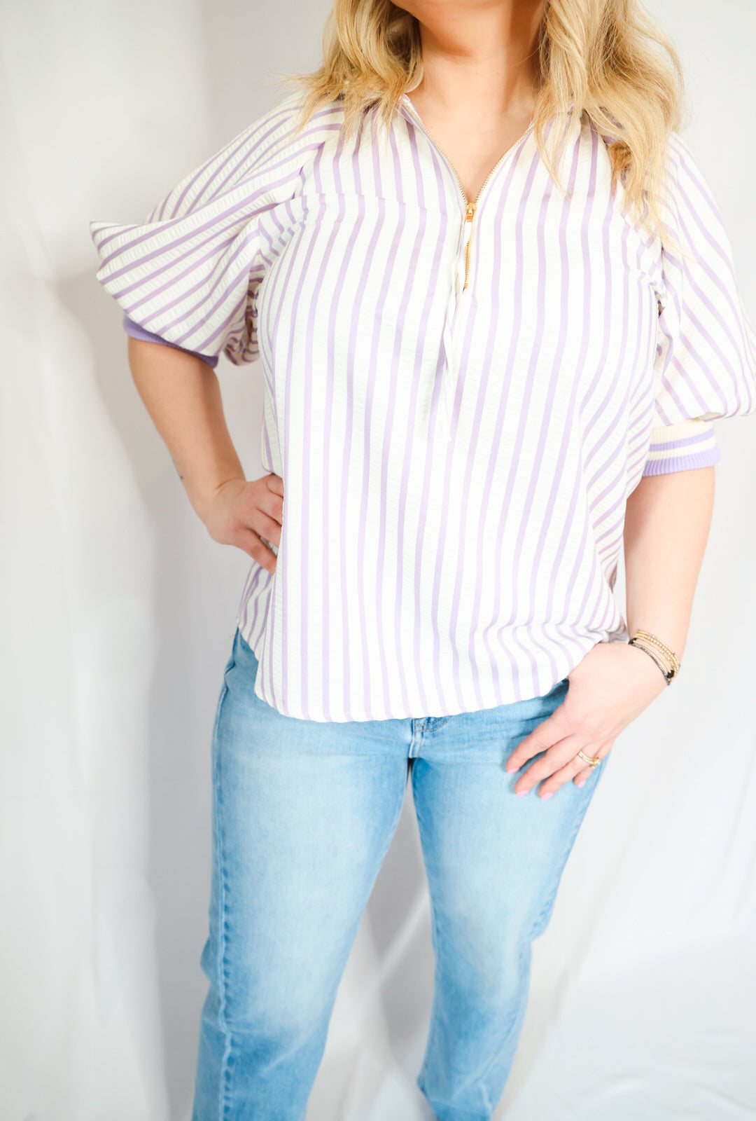 Woman wearing a striped shirt and light blue jeans against a white background
