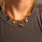 Gold necklace with charms on a gray shirt