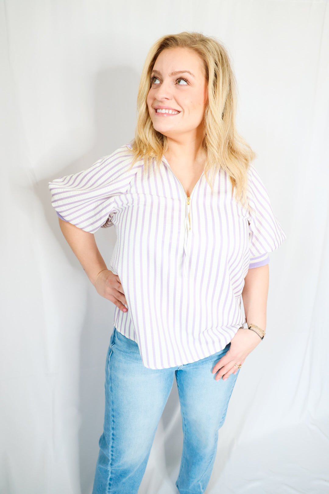 Woman wearing a striped shirt and jeans against a plain background