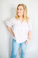 Woman wearing a striped shirt and jeans against a plain background