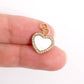 Gold heart-shaped pendant with clear stones held between fingers on a white background