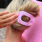 Pink marble-patterned hair tie being used on a bun with a blurred background